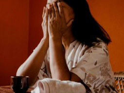 a woman sitting at a table covering her face with her hands